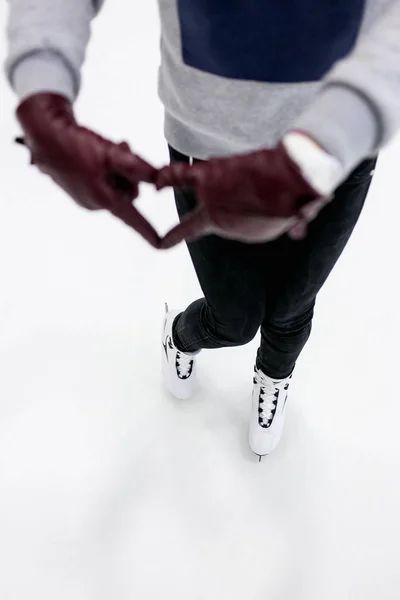 Closeup of girl shows abstract heart symbol by leather gloves on skating rink. Concept  love to skates, winter sports. — Stock Photo, Image