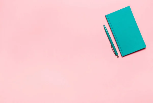 Minimalista plano laico foto de escritorio del espacio de trabajo con cuaderno de aguamarina y pluma en el espacio de copia de fondo rosa. Burla. . — Foto de Stock