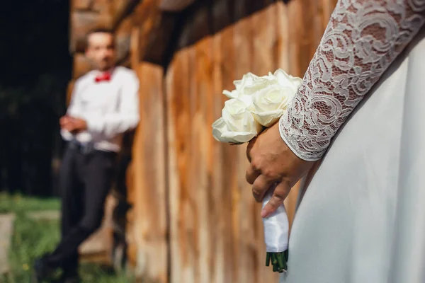 Ramo de novia en novias manos cerrar y el novio en el fondo . — Foto de Stock