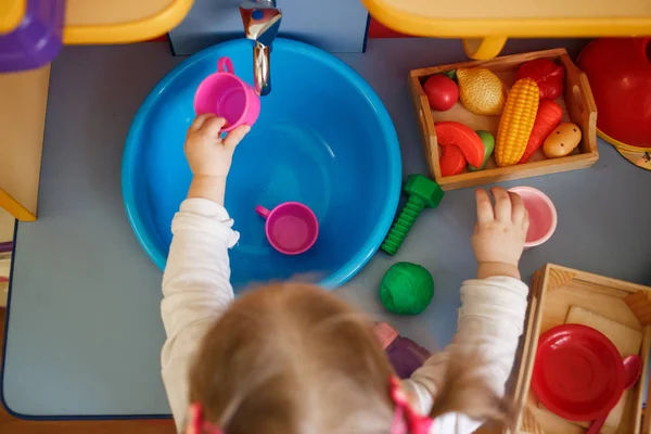 Fata se joacă cu jucării pe o bucătărie mică de jucărie — Fotografie, imagine de stoc