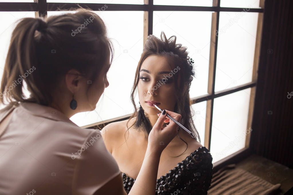 Pretty woman make up artist applying makeup to beautiful latina girl