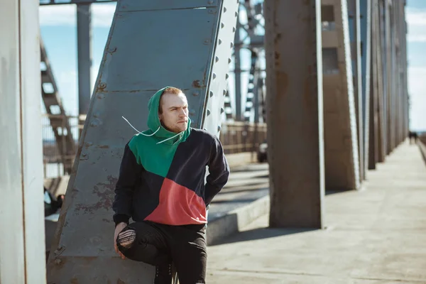 Ung man bär en hoodie-stående av en bro och tittar in avståndet — Stockfoto