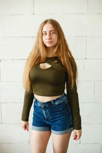 Hermosa joven pelirroja con el pelo largo y rojo posando en luz natural. Ella vistiendo camisas vaqueras y camiseta caqui —  Fotos de Stock