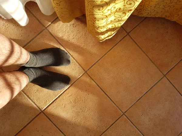 Male feet in socks on ceramic tile in sunny morning