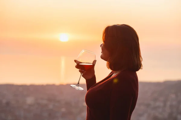 Woman with red wine on sunset mountains, close up of hand holding glass of wine. Elegant woman enjoying beautiful mountain ans sea landscape on sunset — ストック写真