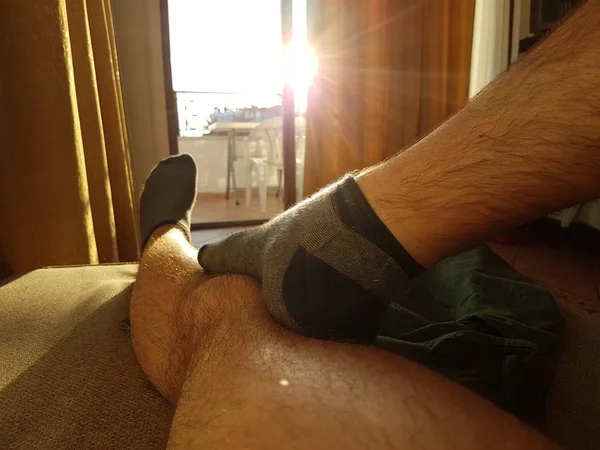 Male feet in the socks closeup on the sofa. Sunny morning.