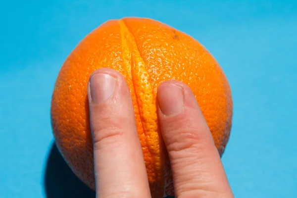 Finger clitoral stimulation abstraction - male fingers ion the juicy vulva-like orange. Direct light flat lay image — Stock Photo, Image