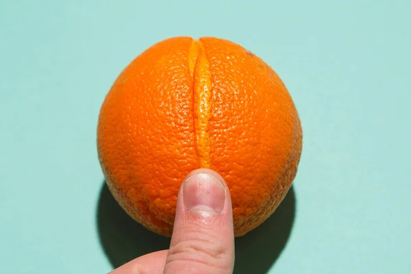 Extracción de estimulación del clítoris con dedos: los dedos masculinos iones de la jugosa naranja similar a la vulva. Luz directa plana imagen laica — Foto de Stock