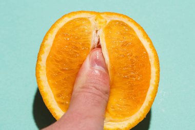Finger clitoral stimulation abstraction - male fingers in the juicy pulp of an orange. Direct light flat lay image clipart