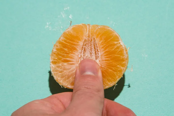 Parmak klitoral uyarılma soyutlaması. Mandalinanın sulu posasında erkek parmakları. Doğrudan ışık düzlüğü görünümü