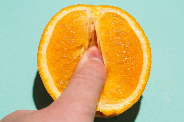 Parmak klitoral uyarılma soyutlaması. Portakalın sulu posasında erkek parmakları. Doğrudan ışık düzlüğü görünümü