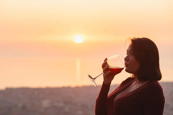 Woman with red wine on sunset mountains, close up of hand holding glass of wine. Elegant woman enjoying beautiful mountain ans sea landscape on sunset — ストック写真