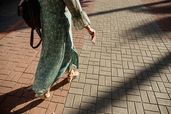 Moda, viajes, concepto de personas. Mujer en un verano ligero vestido verde claro con una mochila y un bolso camina por la acera en tacones — Foto de Stock