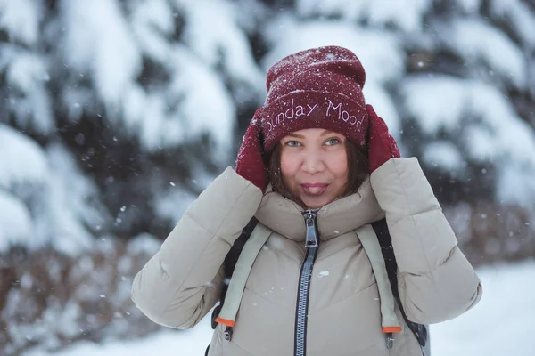 İnsanlar, mevsim ve bayram konsepti. Kış parkında gülümseyen genç bir kadının portresi. Kırmızı kış şapkası ve kırmızı eldivenler giydi. Karlı hava — Stok fotoğraf