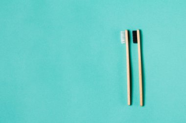 Aquamarine arka planında iki ahşap bambu çevre dostu diş fırçası. Diş bakımı ve sıfır atık konsepti. Düz konum, üst görünüm, kopyalama alanı