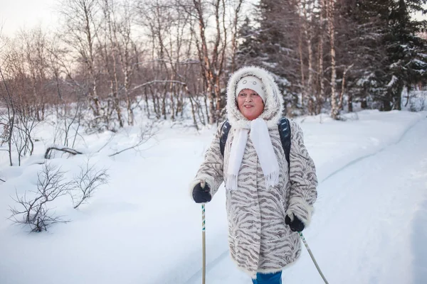 Kış sporu - Kuzey yürüyüşü. Soğuk ormanda yürüyüş yapan yaşlı bir kadın. Mutlu kanlı surat, sağlıklı kan dolaşımı. Kardiyo eğitimi — Stok fotoğraf