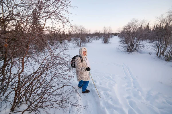 Mutlu, güzel, yaşlı bir kadın kış ormanında İskandinav yürüyüşü yapıyor. Şenlikli bir yaşam tarzı, temiz hava ve iyi bir ruh hali. — Stok fotoğraf