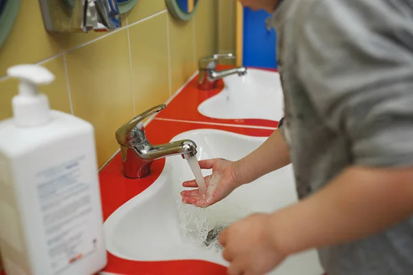 Тоддлеры моют руки в умывальнике в детском саду. Концепция гигиены, профессионального ухода за детьми — стоковое фото