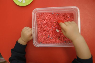 Children play educational games with a sensory bin in kindergarten clipart