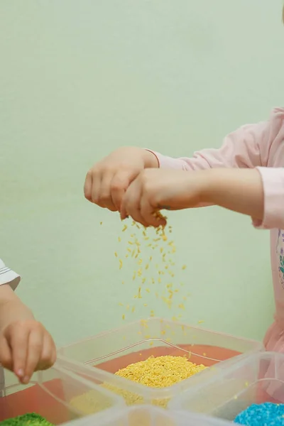 Børn spiller pædagogiske spil med en sensorisk bin i børnehaven - Stock-foto