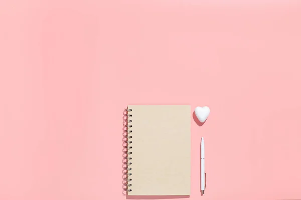 Cuaderno pálido y corazones decorativos blancos sobre fondo rosa. Composición plana. Espacio de trabajo femenino. Romántico, Concepto de San Valentín — Foto de Stock