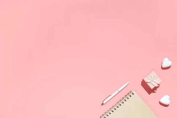 Cuaderno pálido, cajas de regalo de color rosa y corazones decorativos blancos sobre fondo rosa. Composición plana. Espacio de trabajo femenino. Romántico, Concepto de San Valentín — Foto de Stock