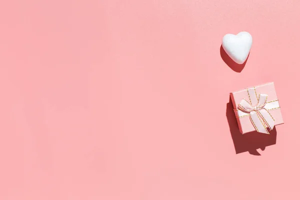 Caja de regalo rosa y corazones decorativos blancos sobre fondo rosa. Composición plana. Romántico, Concepto de San Valentín — Foto de Stock
