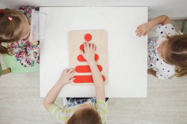 Arkhangelsk, Rusya - 2 Şubat 2019: Beyaz tahtadaki renkli ahşap yapbozlardan renkli heykelcikler toplayan çocuklar. Çocukların okul öncesi gelişimi ve eğitimi