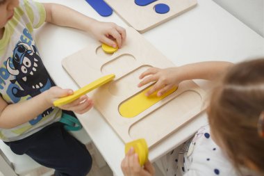 Arkhangelsk, Rusya - 2 Şubat 2019: Beyaz tahtadaki renkli ahşap yapbozlardan renkli heykelcikler toplayan çocuklar. Çocukların okul öncesi gelişimi ve eğitimi