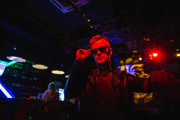 Schöner Mann in Lederjacke mit Sonnenbrille und Neonlicht — Stockfoto