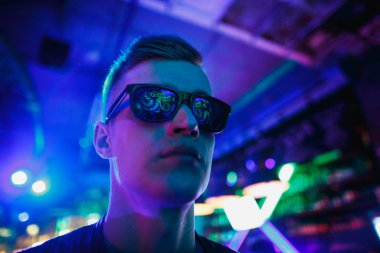 Neon ışıklı gözlüklü bir adamın portresi. Gözlüklerdeki neon yansımaları.