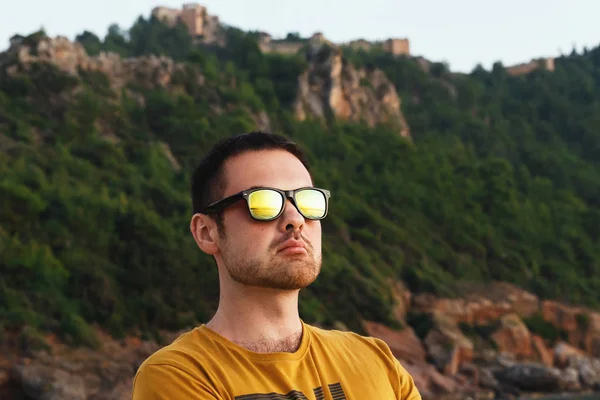 Hombre atractivo en gafas amarillas se relaja en la playa al atardecer —  Fotos de Stock