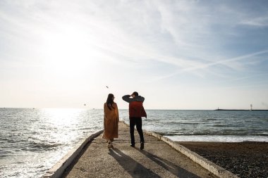 Genç ve şık bir çift rıhtımda geziniyor, baharın başında denizin tadını çıkarıyor.