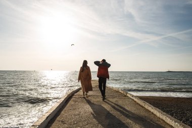 Genç ve şık bir çift rıhtımda geziniyor, baharın başında denizin tadını çıkarıyor.