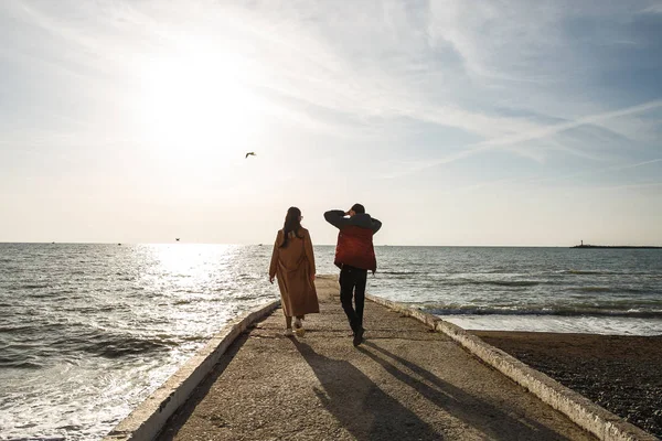 年轻貌美的夫妻漫步在码头，享受早春的大海 — 图库照片