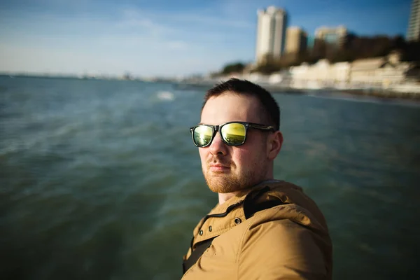 Чоловічий турист в сонцезахисних окулярах бере селфі проти моря. Курорт у низький сезон. Весняне море — стокове фото