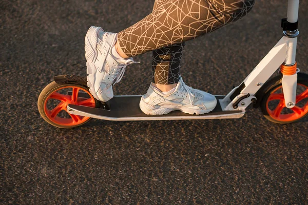 Patas femeninas en zapatillas blancas en una patineta scooter de cerca — Foto de Stock