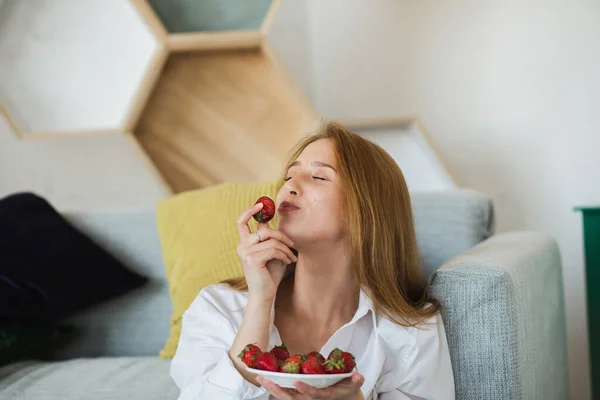 Sexy rubia disfruta de deliciosa fresa en la sala de estar — Foto de Stock