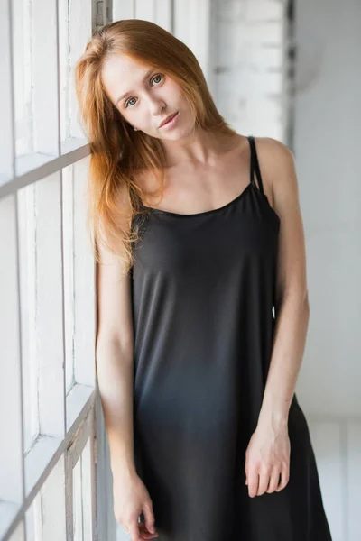 Молодая чувственная блондинка в черном сексуальном платье позирует у окна — стоковое фото