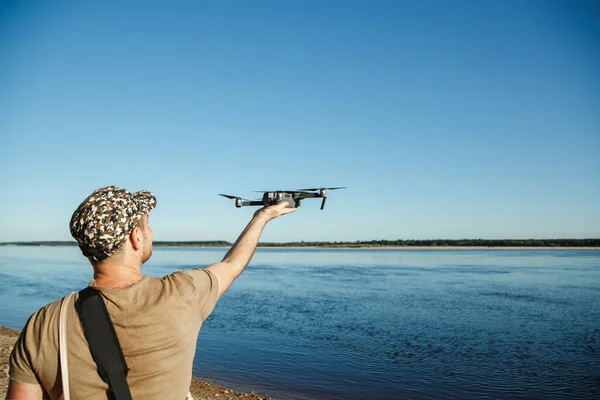 Mannelijke toerist lanceert drone van de hand in de buurt van rivier — Stockfoto