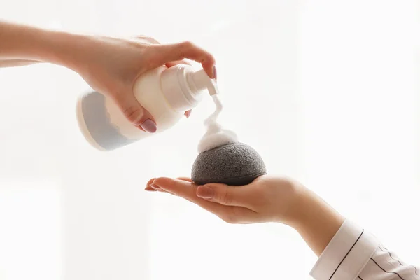 Womens hands apply foam to sponge foundation on a white background