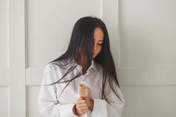 Bella giovane donna abbottonando la camicia mentre si veste o si spoglia mentre la cambia o pensa — Foto Stock