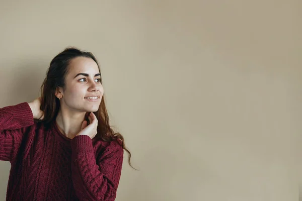 Mujer latina joven feliz en suéter de clarete posando sobre fondo beige. De aspecto amistoso. Copiar espacio . — Foto de Stock