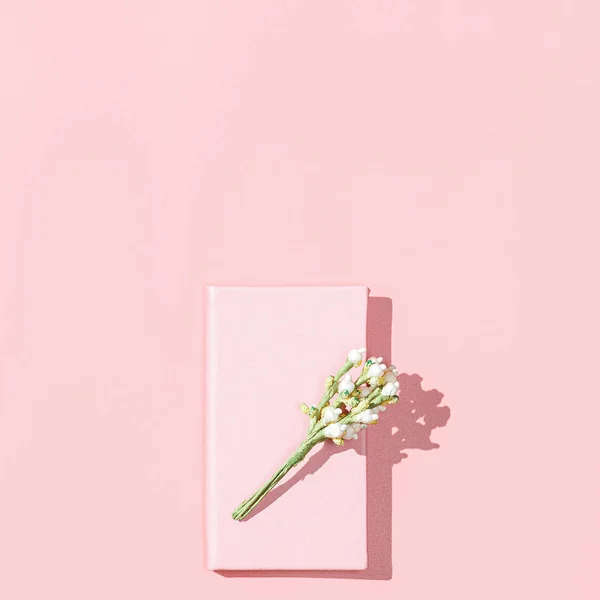 Minimalistisk kort mockup med tom rosa anteckningsbok, vit penna, blomma blomma gren på rosa bakgrund. Vårens feminina bloggarkoncept. Platt låg, fyrkantig bild, ovanifrån, kopiera utrymme — Stockfoto