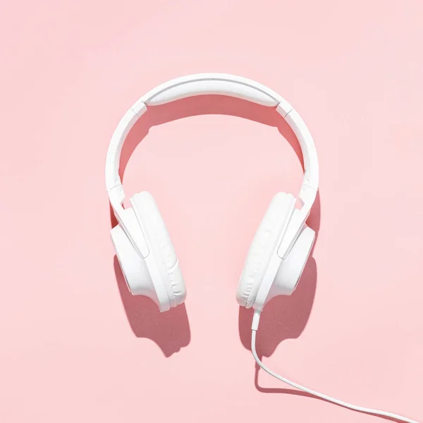 Flat lay white headphones on modern pale pink table wallpaper. Free space for creative design text and content — Stock Photo, Image