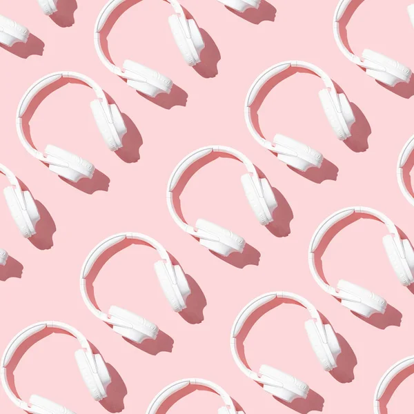 Patrón auriculares blancos en la moderna mesa de color rosa pálido vista superior plana laico. Espacio libre para texto y contenido de diseño creativo —  Fotos de Stock