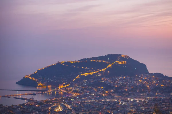 Vue du soir depuis les montagnes jusqu'à la partie centrale d'Alanya, Turquie. Château d'Alanya avec éclairage . — Photo