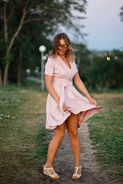 Prachtig vrolijk meisje in de dans op het groene gras. Een delicate roze jurk fladdert prachtig. Dynamisch portret van boven — Stockfoto