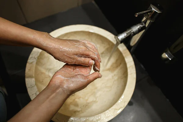 Женщина моет руки с мылом в ванной комнате в общественном месте. Тщательная профилактика мытья рук против патогенных вирусов и бактерий — стоковое фото