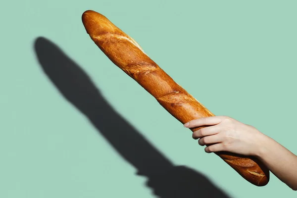 Female hands hold a bread loaf on green background. Flat lay, direct light — Stock Photo, Image